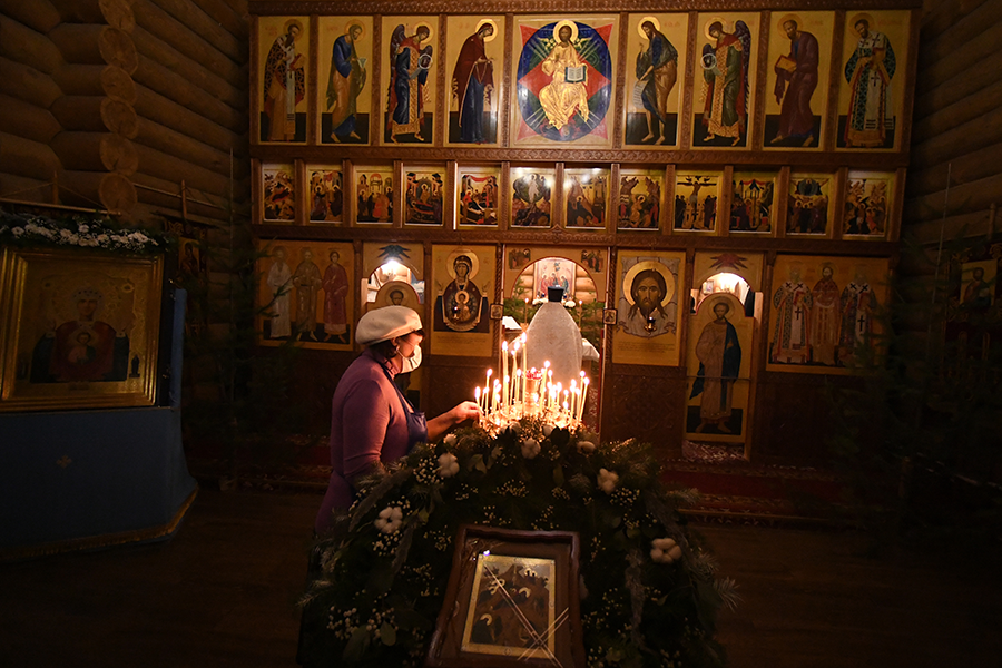 Женщина ставит свечу во время ночной Рождественской службы в православной Знаменской церкви в городе Дивногорске Красноярского края