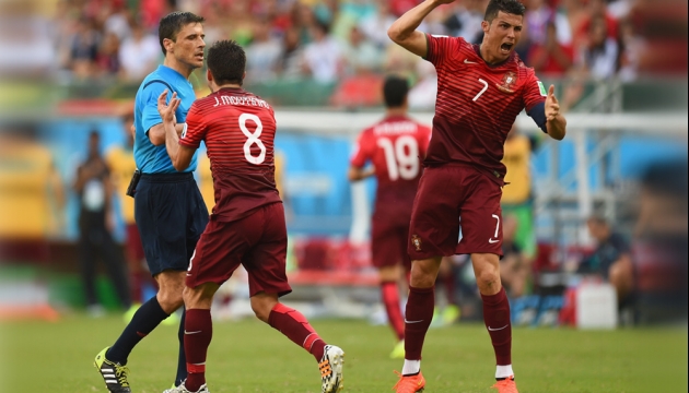 Игроки сборной португалии Жоау Моутинью (слева) и  Криштиану Роналду спорят с рефери Милорадом Мажичем  во время матча в Группе G Германия - Португалия. 