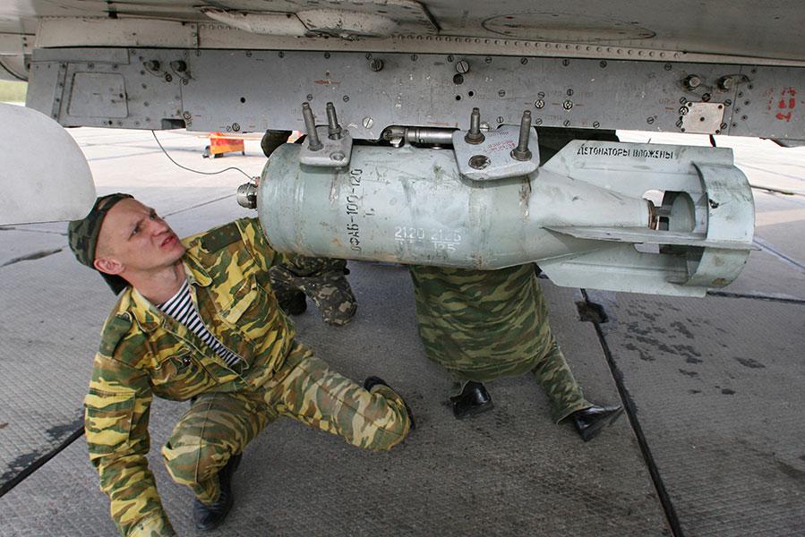 Техник вооружений крепит на внешней подвеске штурмовика Су-24М осколочно-фугасную авиационную бомбу (ОФАБ) на военном аэродроме в Черняховске, 2011 год