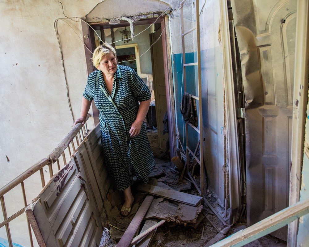 Жительница Славянска выходит из своей разрушенной попаданием снаряда квартиры