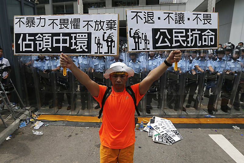 Протестующий держит плакаты, на которых написано: Occupy Central&nbsp;и&nbsp;&laquo;Гражданское неповиновение&raquo;.&nbsp;