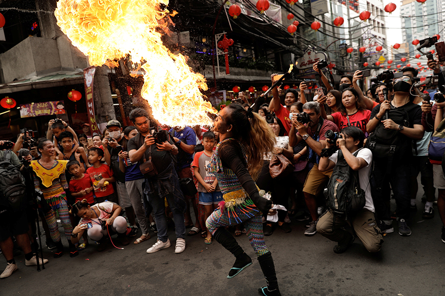 Каскадер выпускает изо рта языки пламени на улицах Манилы
