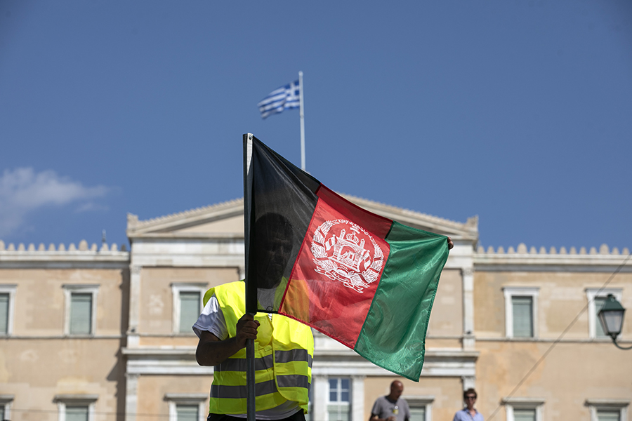Протестующий разворачивает афганский флаг во время митинга в Афинах