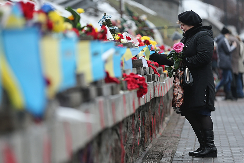 Женщина возлагает цветы к памятнику жертвам Майдана
