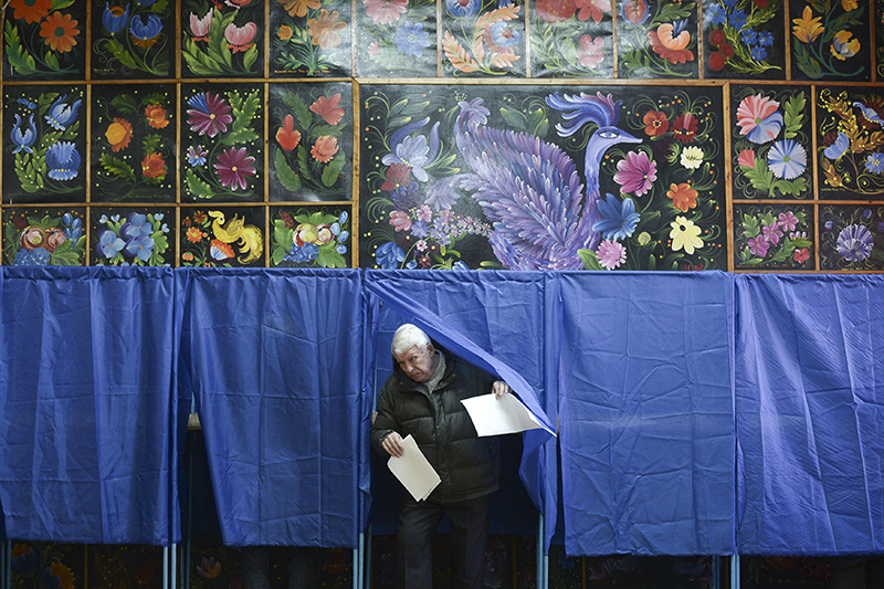 Мужчина выходит из кабинке для голосования на избирательном участке в Киеве.