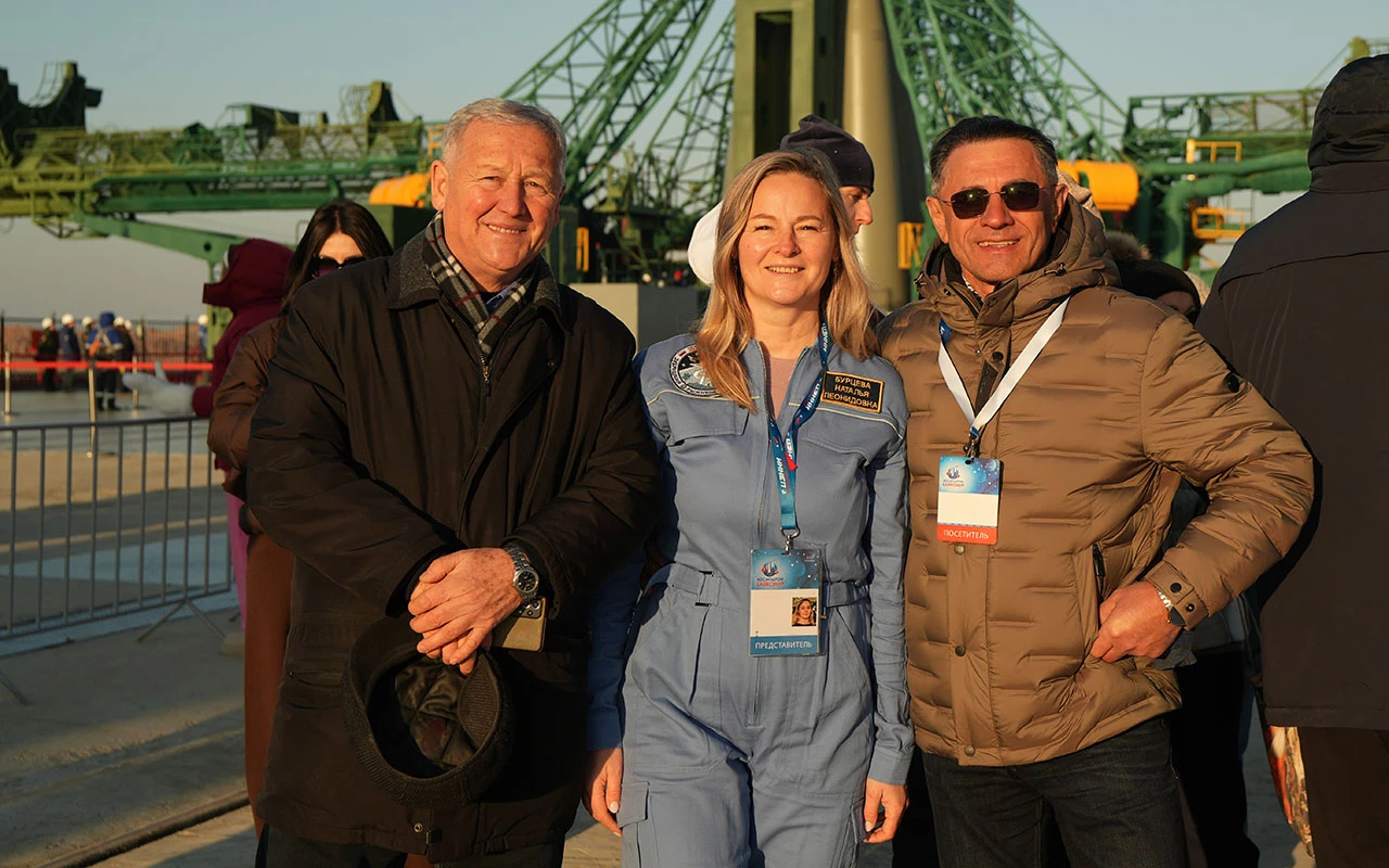 Победители акции «СберПервого» и СК «Сбербанк страхование жизни» на фоне вертикализированной ракеты-носителя «Союз 2.1а» на стартовой площадке космодрома