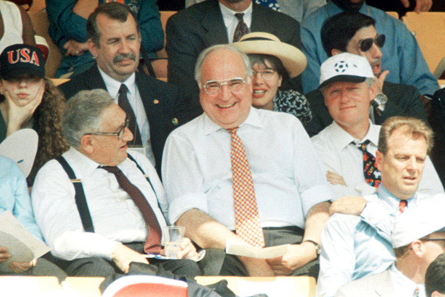 Бывший госсекретарь США Генри Киссинджер (слева), канцлер ФРГ Гельмут Коль (по центру) и&nbsp;президент США Билл Клинтон (справа) во&nbsp;время матча сборных Германии и&nbsp;Боливии на&nbsp;чемпионате мира по&nbsp;футболу. 1994&nbsp;год,&nbsp;США.