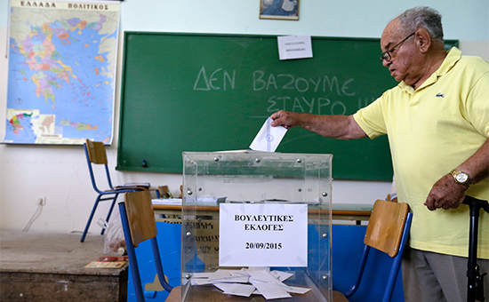 Мужчина опускает бюллетень в урну на одном из избирательных участков в Афинах