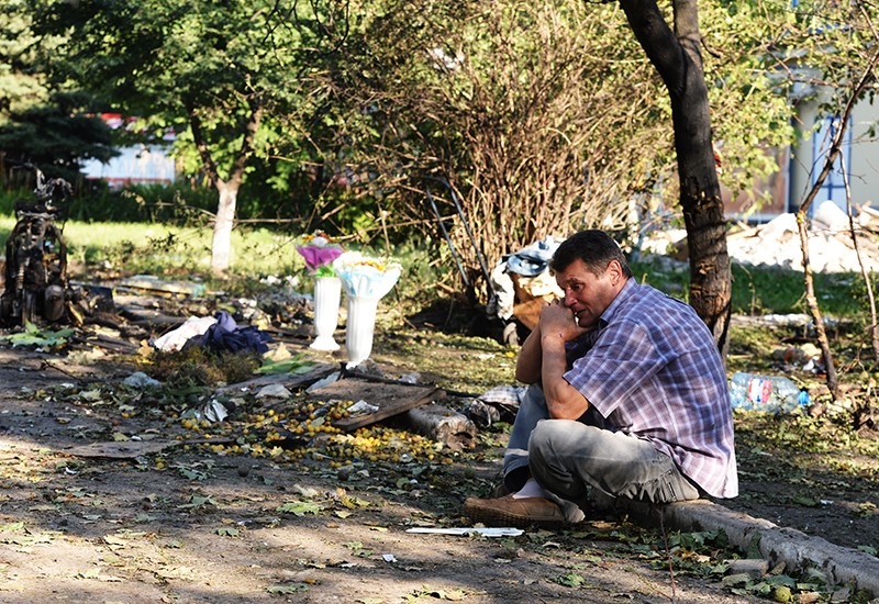 Мужчина на месте гибели родственника в Горловке, подвергшейся ракетно-минометному обстрелу.