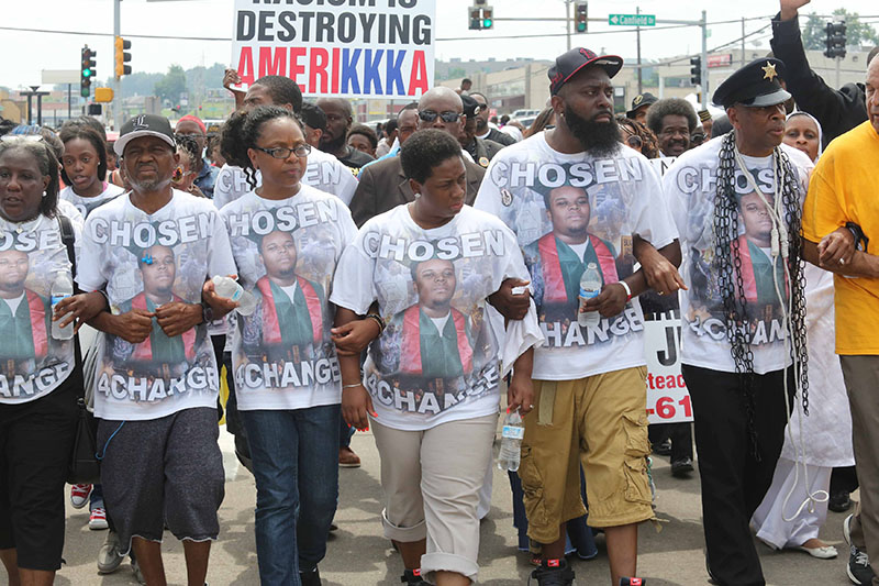 Колонна протестующих на митинге памяти Майкла Брауна в Фергюсоне 9 августа. Второй справа&nbsp;&mdash;&nbsp;отец убитого подростка Майкл Браун-старший. &laquo;Избранный ради перемен&raquo;,&nbsp;&mdash; гласит надпись на футболках с изображением Брауна-младшего