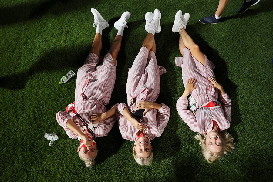 Спортсмены из Швейцарии лежат на траве во время церемонии закрытия