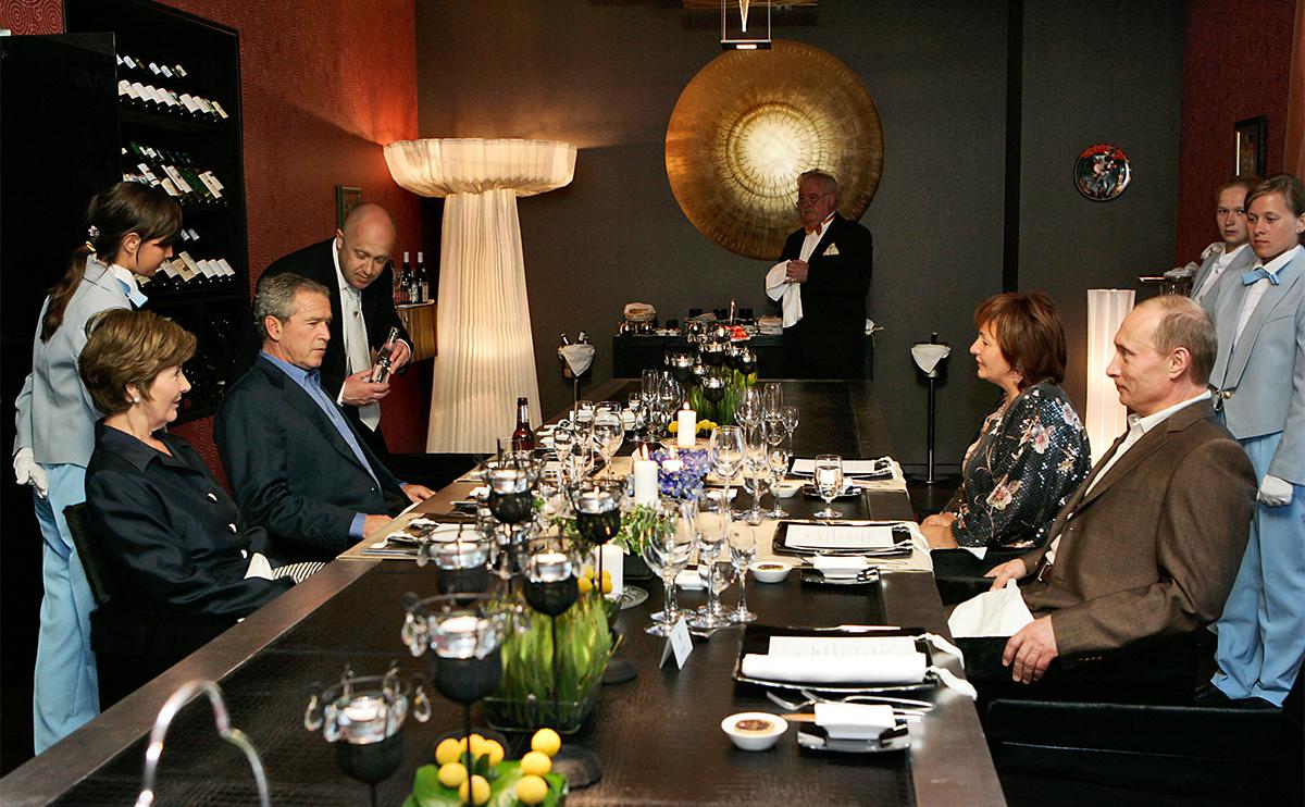 Джордж Буш,&nbsp;его жена Лора (сидят слева),&nbsp;Владимир Путин и его бывшая супруга Людмила (сидят справа)&nbsp;во время неформального ужина 14 июля 2006 года. Евгений Пригожин стоит рядом с&nbsp;Бушем