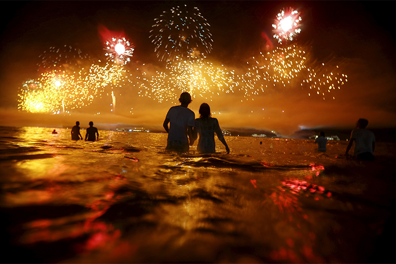 Посетители пляжа Копакабана&nbsp;в Рио-де-Жанейро&nbsp;наблюдают за новогодним салютом
