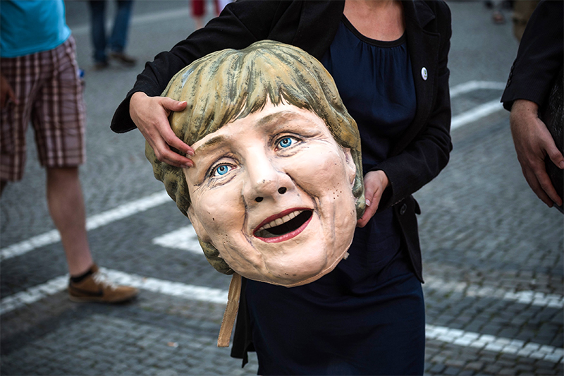 Ангела Меркель&nbsp;и политика Германии стали одними из главных мишеней для критики демонстрантов. На фото женщина держит в руках муляж головы германского канцлера.