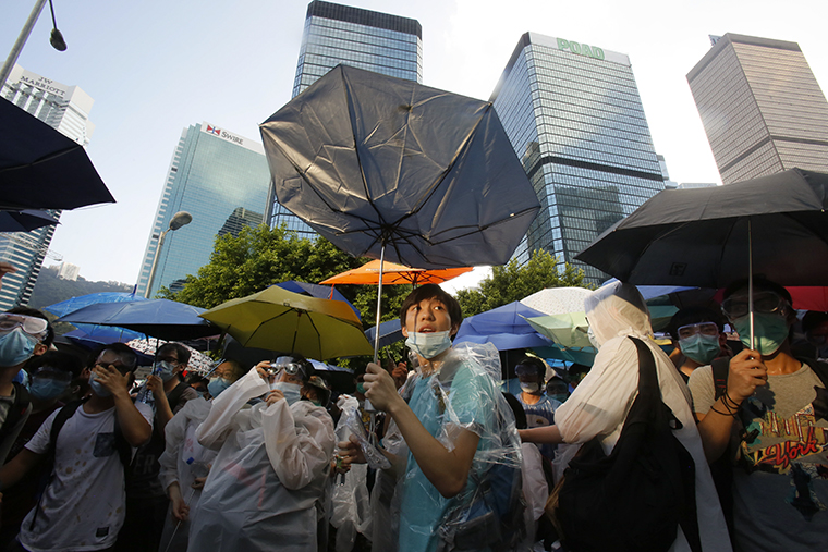 Демонстранты прикрываются зонтиками, чтобы защититься от перцового газа.