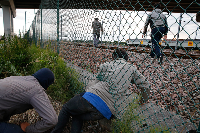 Нелегальный мигрант пытается пролезть под забором на северо-западе Франции, чтобы попасть в Евротоннель под Ла-Маншем


