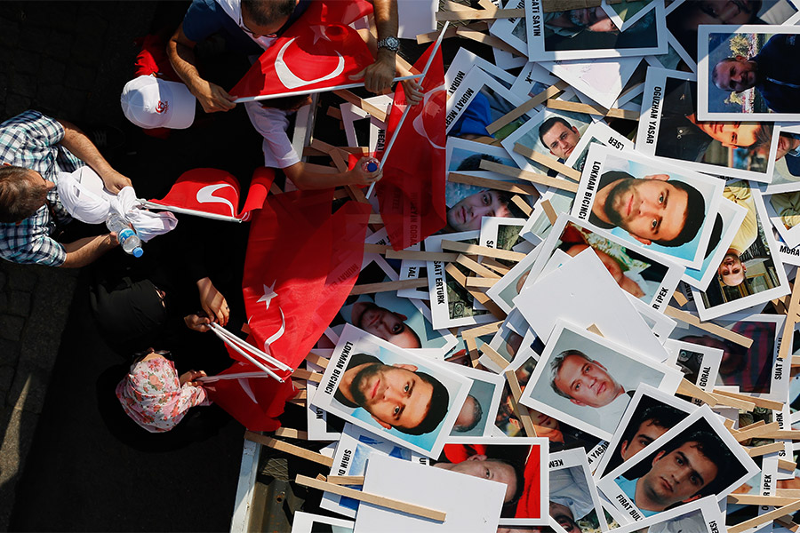 Люди перед началом Марша национального единства в Стамбуле выбирают баннеры с изображениями жертв неудачной попытки госпереворота в 2016 году. Тогда в Турции погибли 250 человек, которые пытались противостоять заговорщикам.
