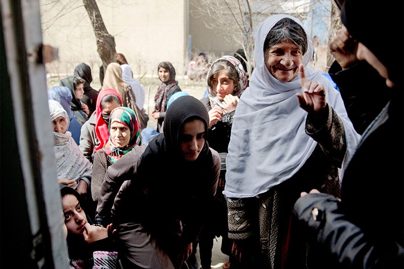 19 марта 2014 г.На окраине Кабула женщины заходят в класс, чтобы зарегистрироваться и получить карточки избирателя на выборах президента Афганистана.