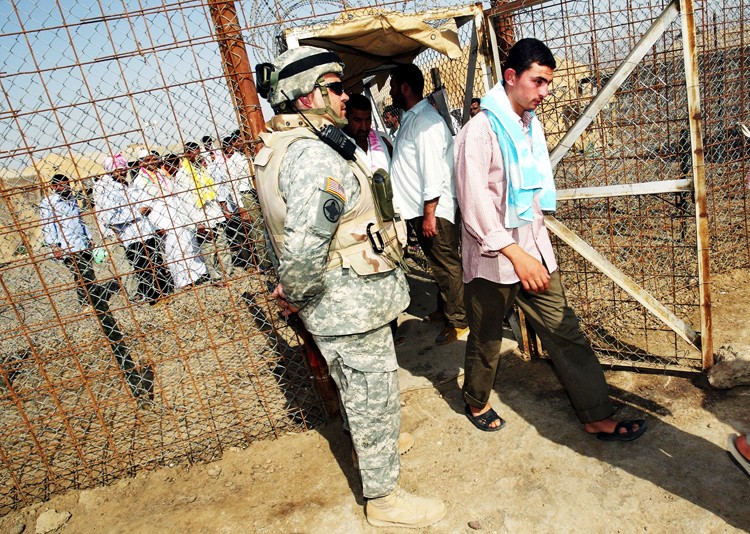 Июнь 2006г. Американский солдат охраняет один из входов в "Абу-Грейб", которую покидают освобожденные из-под стражи заключенные. В соответствии с принятым в стране планом национального примирения тогда были освобождены более 500 заключенных-иракцев.