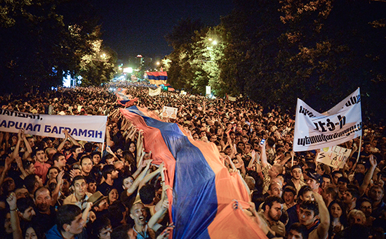 Протестующие несут огромный национальный флаг во время акции протеста против повышения цен на электроэнергию в Ереване