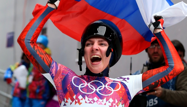 Никитина водрузила над собой российский флаг, радость от олимпийской медали зашкаливает.