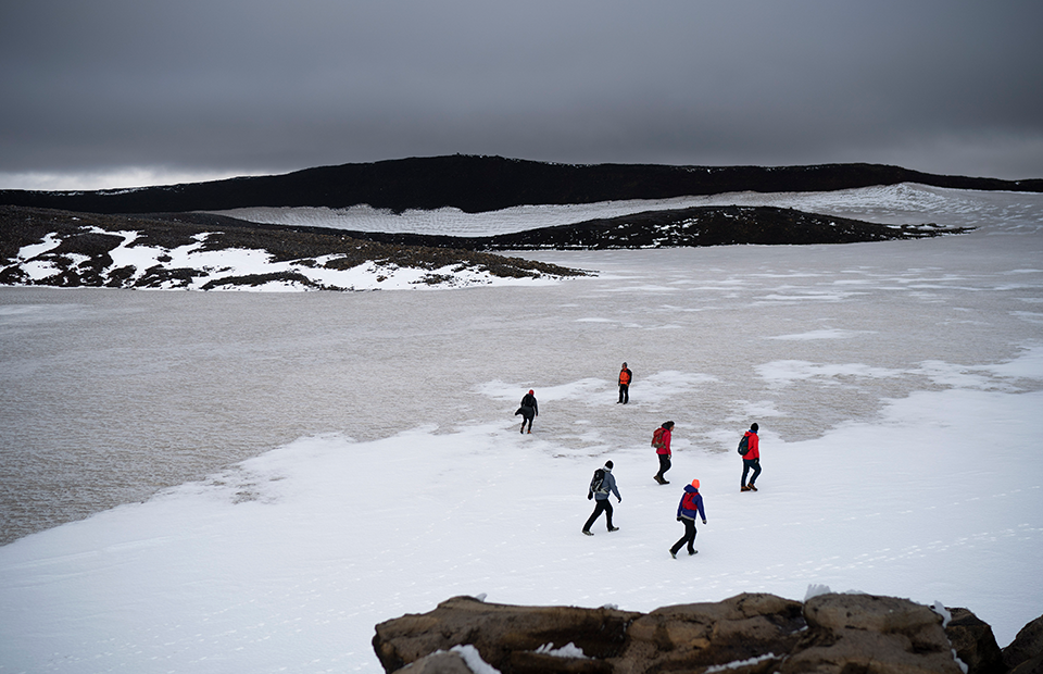 Исландские официальные лица и активисты идут по заснеженному кратеру вулкана в том месте, где раньше был ледник Окйокуль. 18 августа 2019 года
