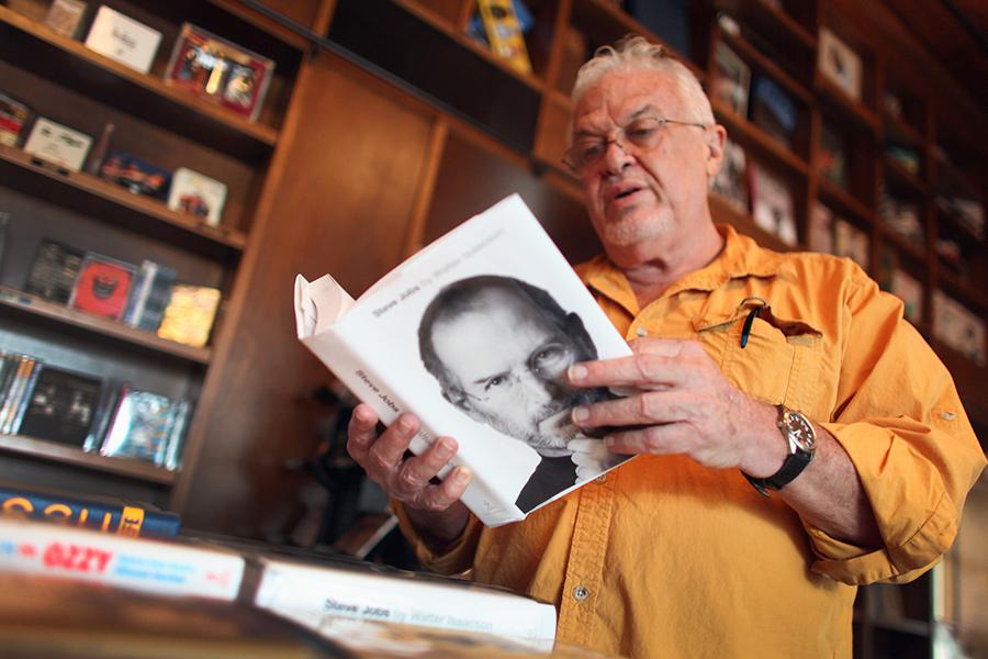 Мужчина читает биографию Стива Джобса от Уолтера Айзексона