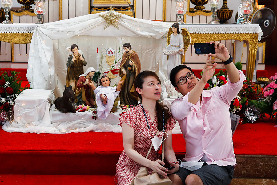 Пара фотографируется в церкви в Бангкоке после рождественских богослужений. На фоне распространения омикрон-штамма коронавируса&nbsp;посетителей храмов обязали носить маски и соблюдать дистанцию