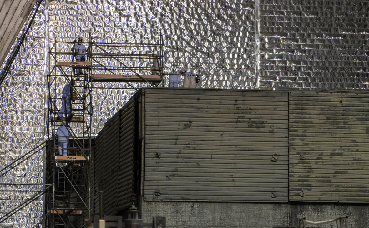 Рабочие около разрушенного в результате аварии 4-ого энергоблока Чернобыльской АЭС под изоляционным арочным сооружением