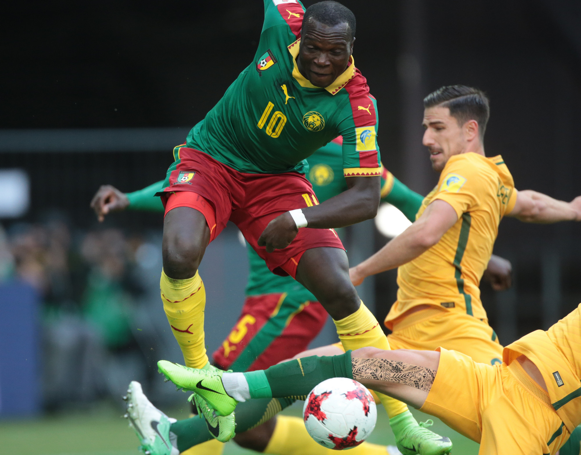 Два австралийских футболиста атакуют нападающего сборной Камеруна Венсана Абубакара (№&nbsp;10)