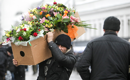 Продавец несет коробку с&nbsp;букетами цветов в&nbsp;Москве