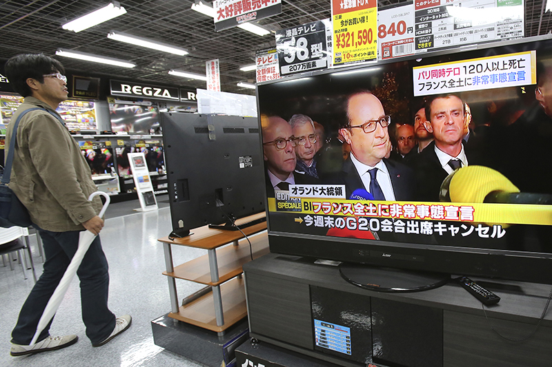 Люди смотрят новости по телевидению в Токио
