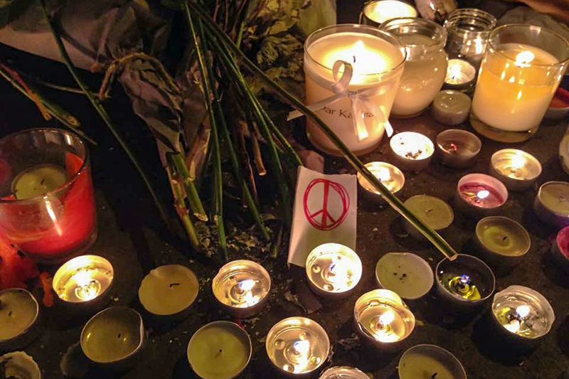 Принесенные парижанами цветы и свечи на месте убийства
