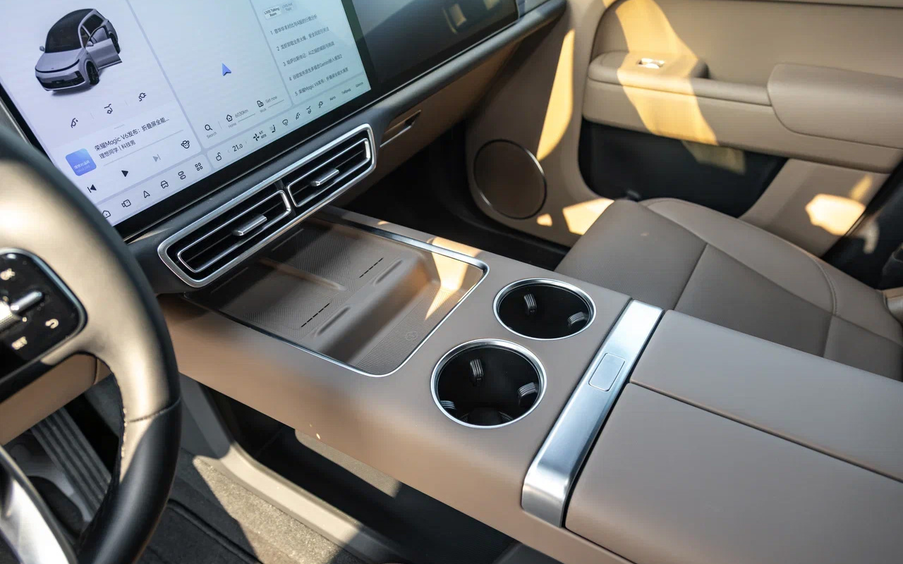 Перед парой площадок для смартфонов с индукционной зарядкой нашлось место для неглубокой ниши. Задумка здравая, но реализация хромает: на виражах предметы из нее перманентно вылетают