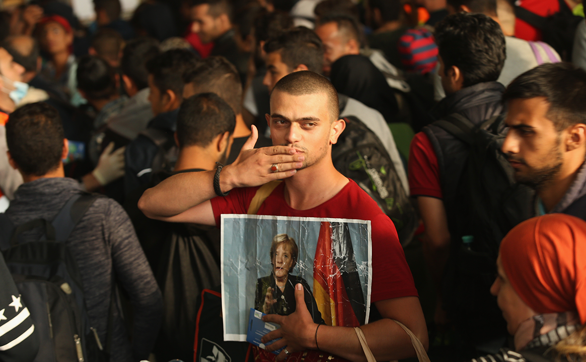 Мигрант из Сирии держит фотографию канцлера Германии Ангелы Меркель