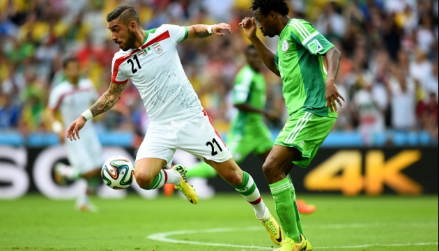 Иранец Ашкан Дежага бросает вызов  нигерийцу Эфе Амброузе во время матча в Группе F Иран - Нигерия. 