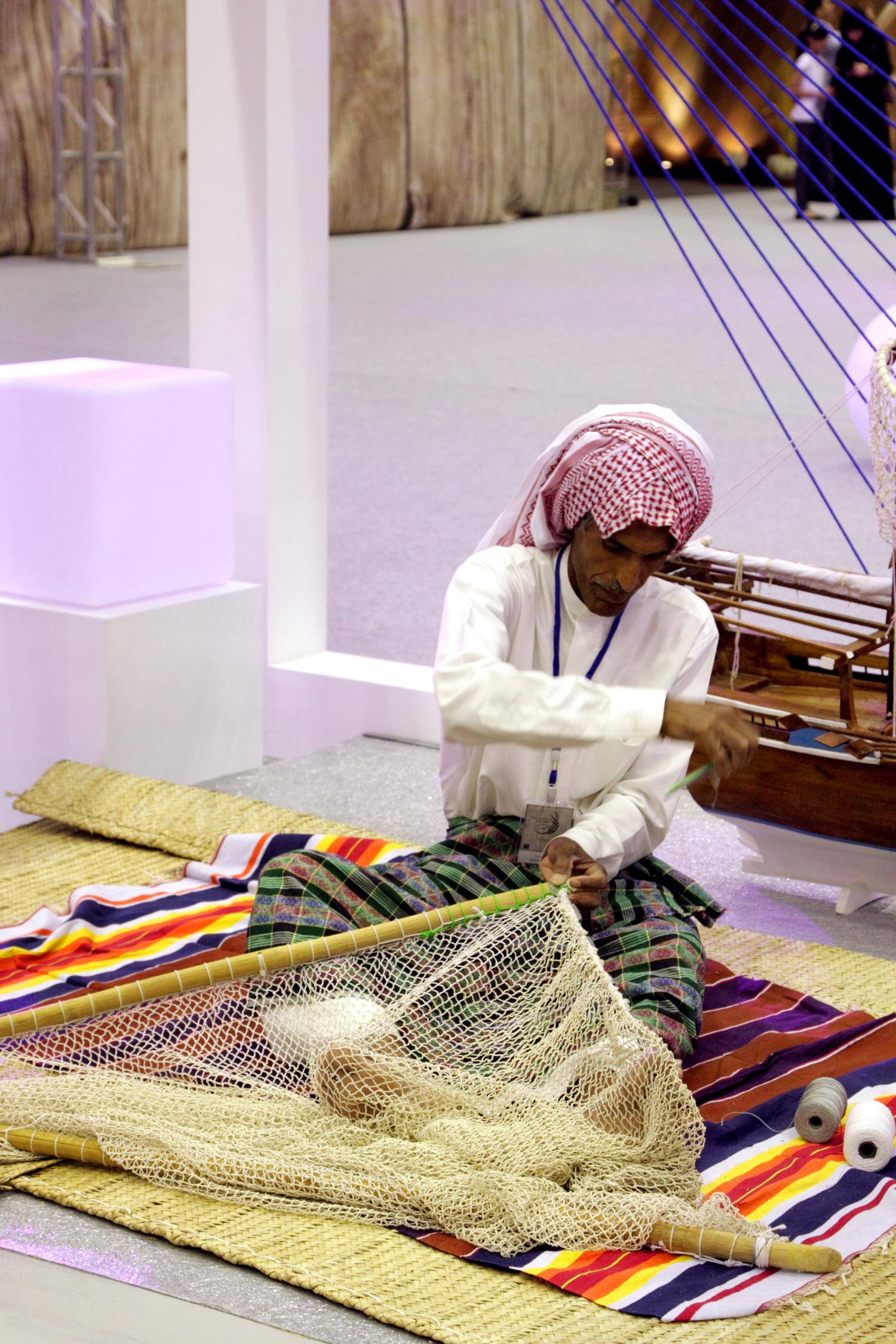 Мастер плетет рыболовную сеть во время фестиваля народного наследия