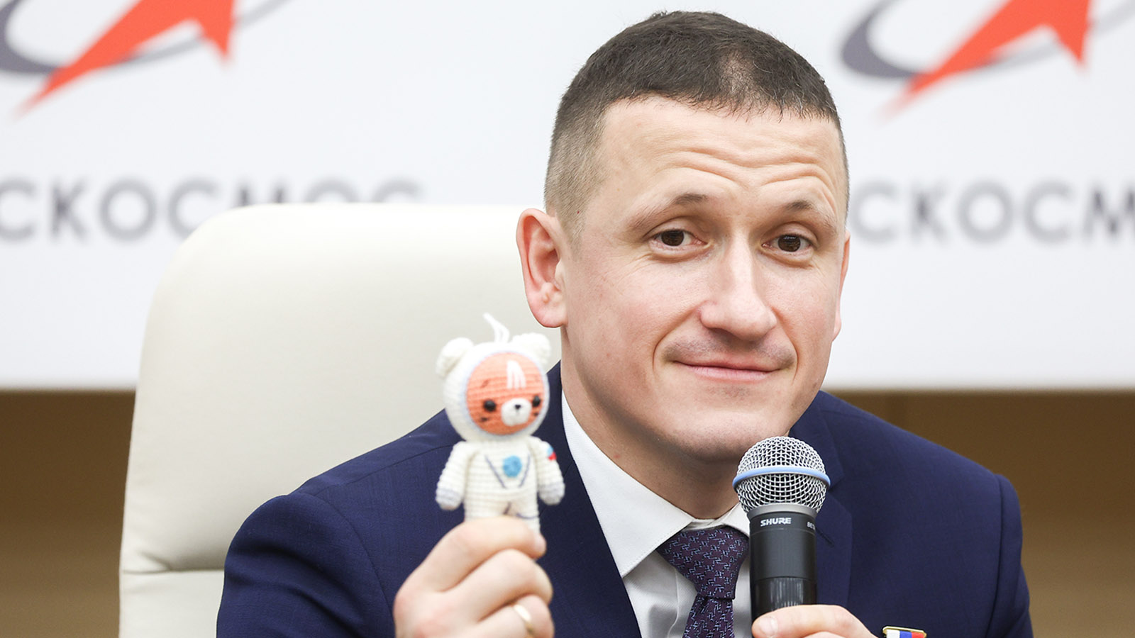Сергей Кудь-Сверчков во время предполетной пресс-конференции основного и дублирующего экипажей экспедиции МКС-74 и индикатор невесомости в виде кота