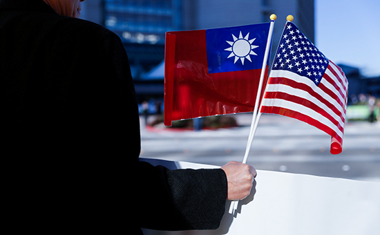 Демонстрант держит в руке флаги Тайваня и США. Калифорния, США



