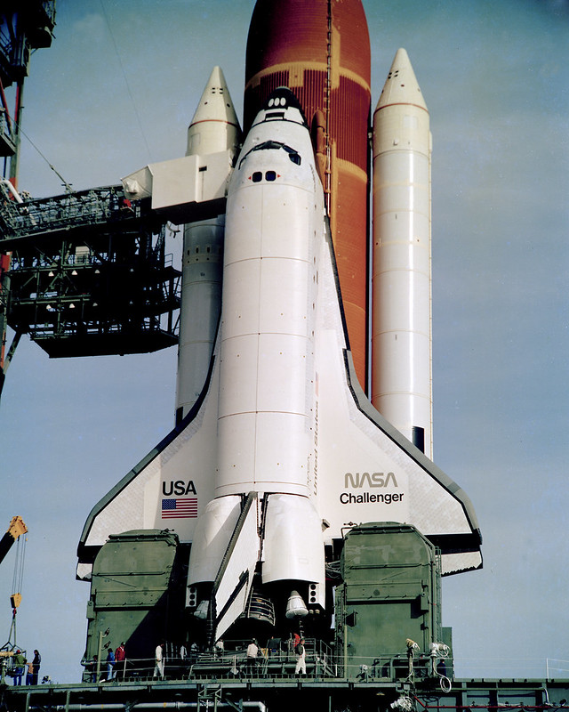 На этом снимке космический челнок &laquo;Челленджер&raquo; ожидает на стартовом комплексе перед запуском своей первой миссии STS-6 4 апреля 1983 года. Он стал вторым действующим &laquo;шаттлом&raquo;, доставленным в Космический центр имени Кеннеди в июле 1982 года. &laquo;Челленджер&raquo; был уничтожен вскоре после старта во время 10-й миссии STS-51L 28 января 1986 года.