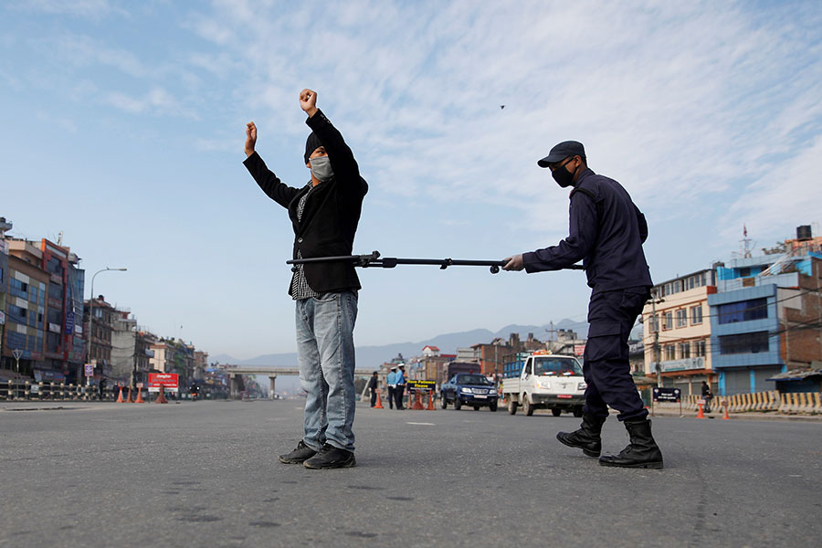 Полицейский задерживает нарушителя режима самоизоляции, пытаясь соблюдать дистанцию. Катманду, Непал
