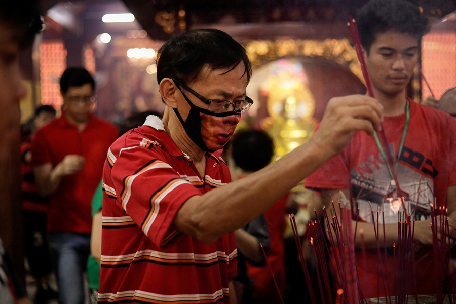 Мужчина зажигает ароматические палочки во время празднования китайского лунного Нового года в храме в Бинондо (Манила)