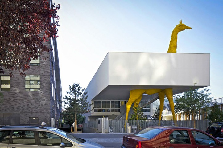 Giraffe сhildcare center ("Жираф")Фасад детского сада в пригороде Парижа (Франция) выполнен архитекторами студии Hondelatte Laporte Architectes из белого рифленого железа. Крышу строения пронзает желтый жираф, который как будто ест листья с близлежащих деревьев, рядом стоит белый медведь.