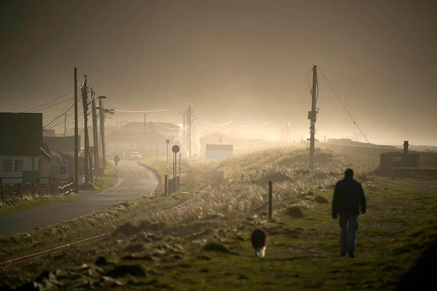 <p>На фото: житель Уэльса (Великобритания) прогуливается вдоль морских укреплений, установленных из-за подъема уровня моря, 3 января 2020 года</p>