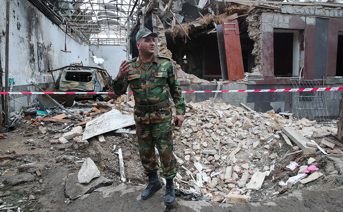 Азербайджанский военнослужащий около здания, разрушенного в результате обстрела города Гянджа