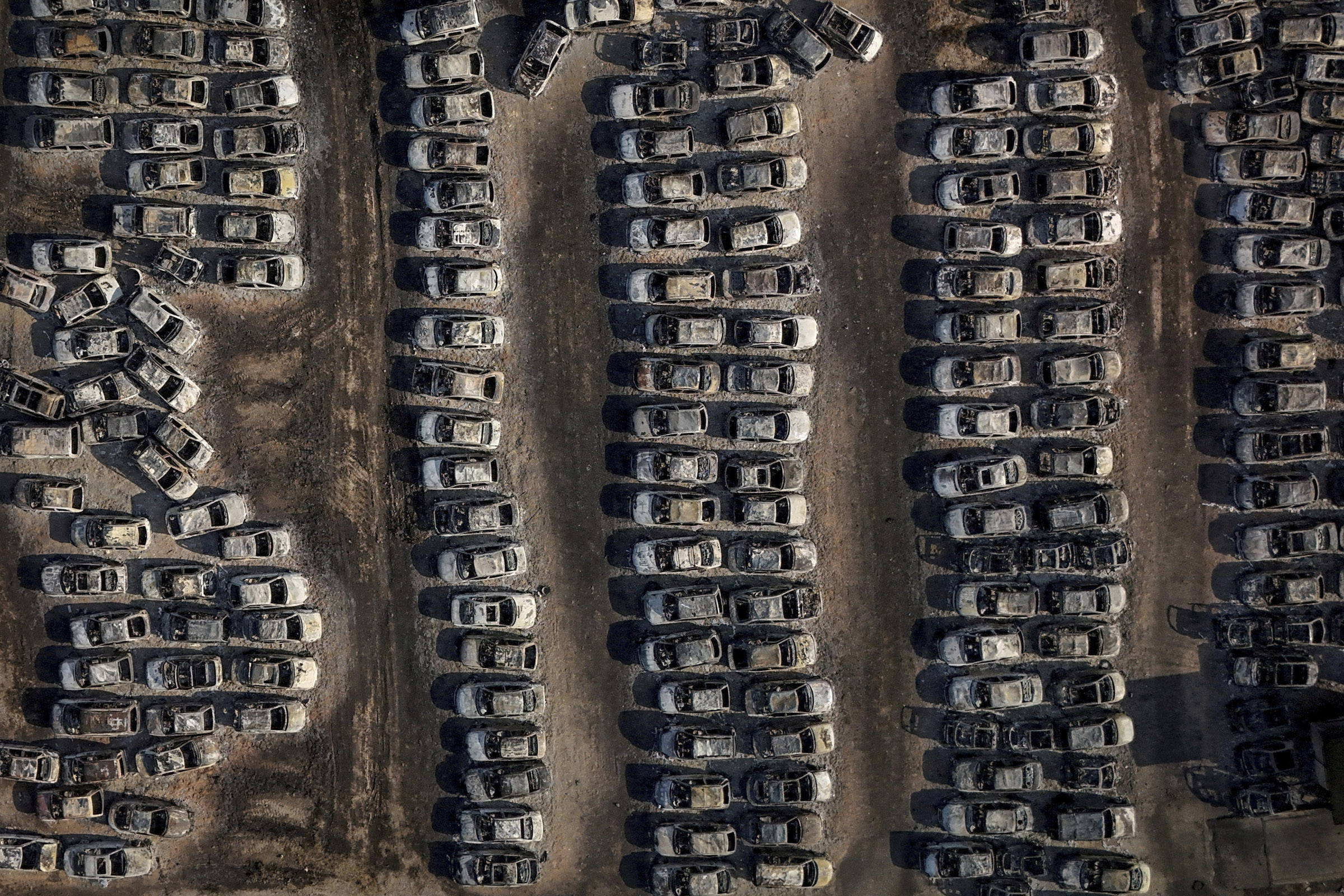 Автомобили, сгоревшие во время бушевавшего летом в Греции лесного пожара. В районе города Патры пламя добралось до местных заводов, а также до автомобильной парковки, где превратило сотни машин в металлолом. 14 августа 2025 года

