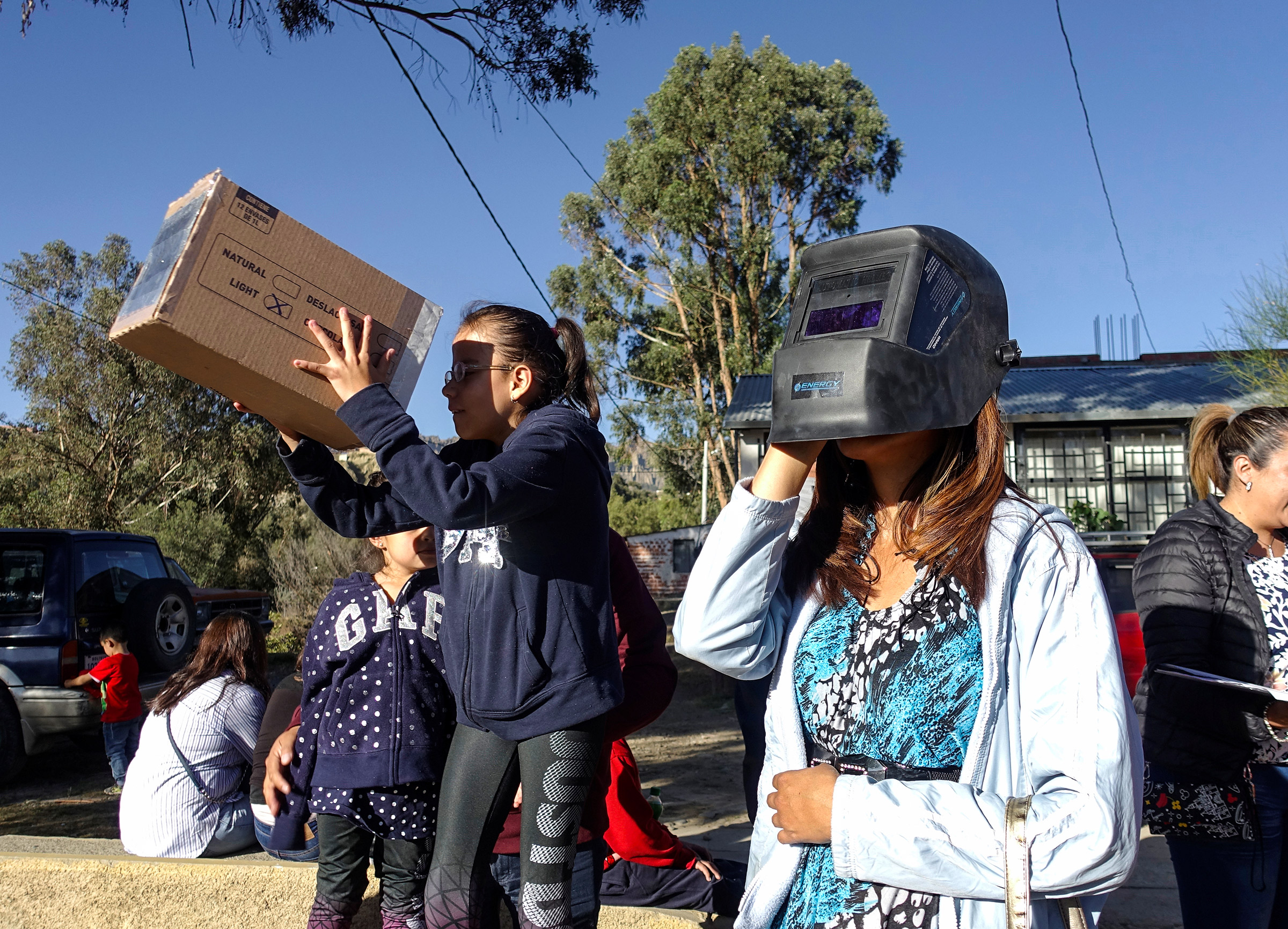 Люди смотрят на затмение с помощью специальных очков в боливийском Ла-Пасе