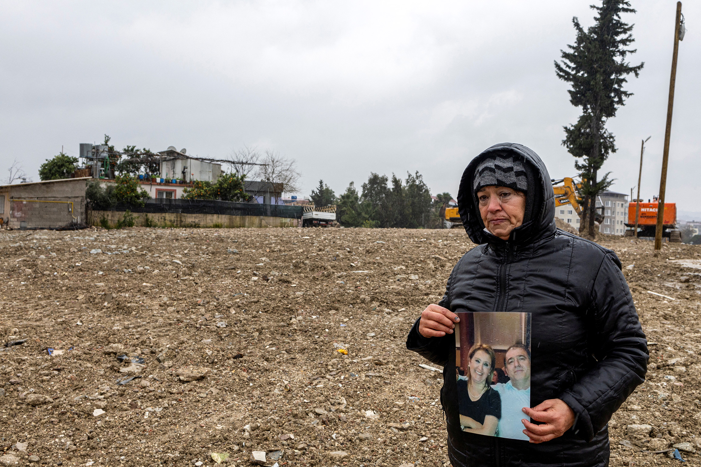 Айсун Челенк держит фотографию сестры Берны и ее мужа Кемаля, которые пропали без вести во время землетрясения, фото сделано на месте их уже снесенного дома. Хатай, 30 января.