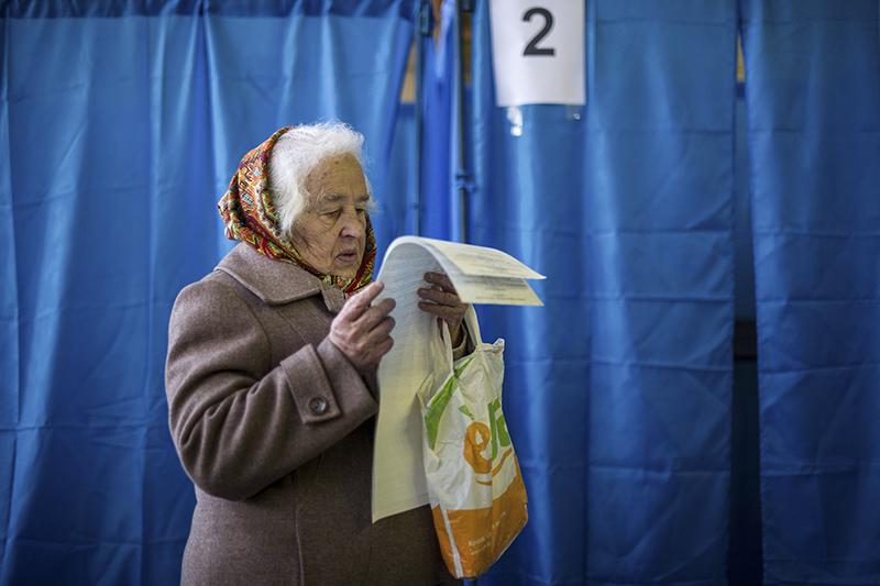 Пожилая женщина с бюллетенями у кабинки для голосования на досрочных выборах депутатов парламента Украины.