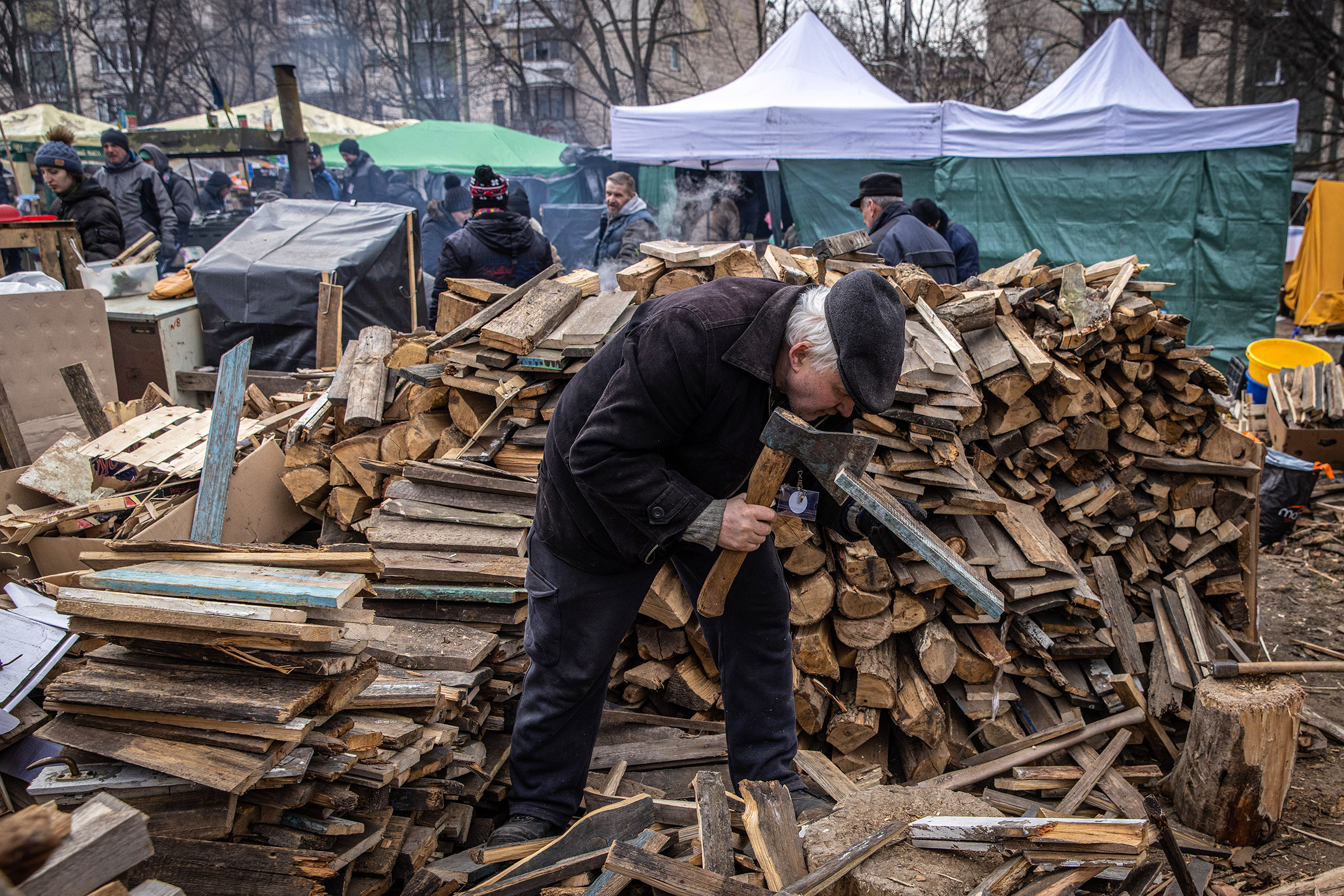 Киев, Украина. Доброволец рубит дрова для костров в придорожном лагере волонтеров, чтобы помочь приготовить и раздать еду нуждающимся, 9 марта